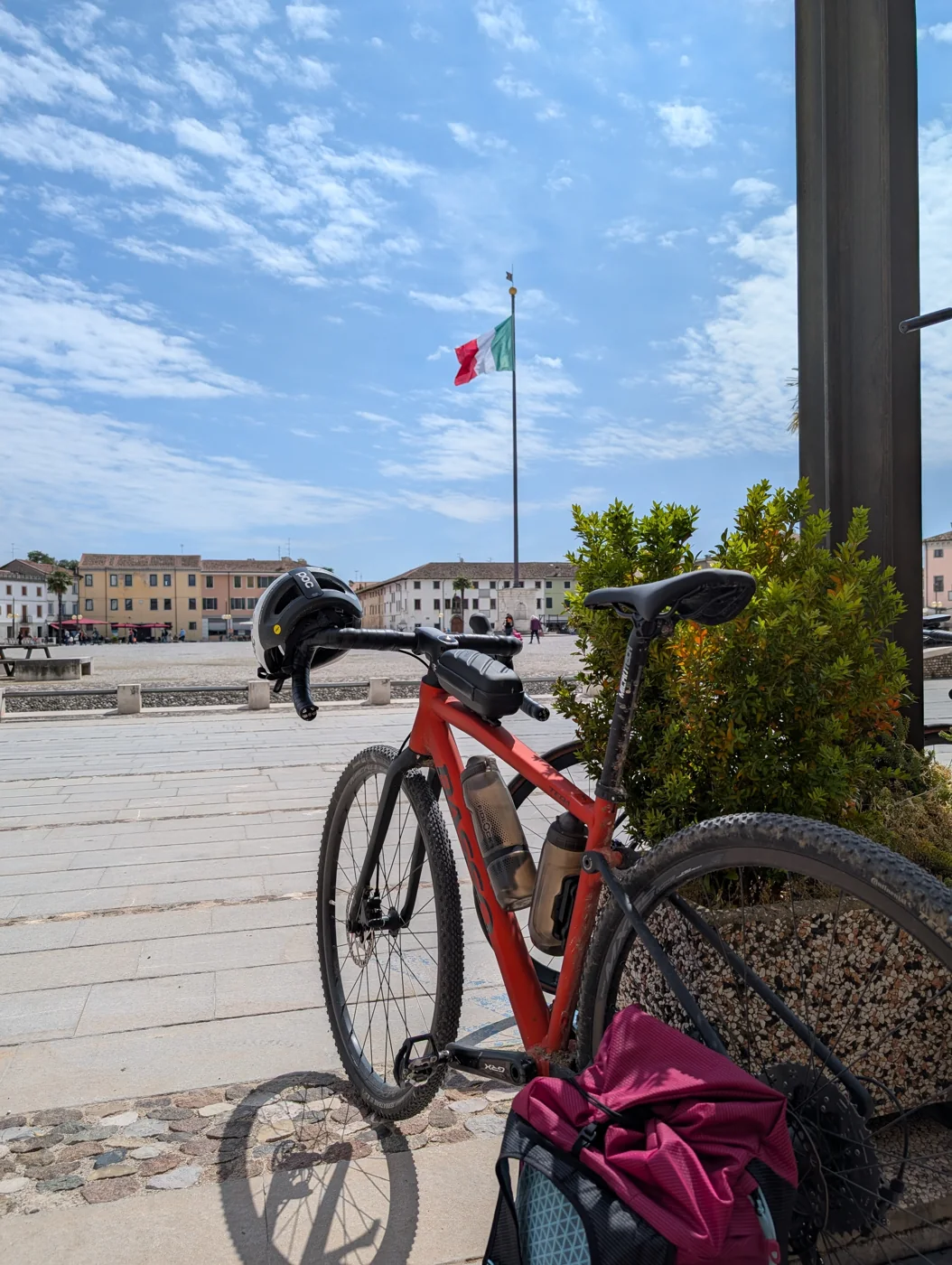 Rotes Gravelbike bei einer Pause auf einem italienischen Platz